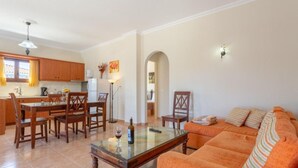 A living room with a sofa, a coffee table, and a dining area with chairs and a table. - Villa Mansion With Private Pool (Zakynthos)