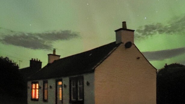 A house with a white exterior and a dark roof, under a greenish sky with stars visible. - 2 bedroom accommodation in Castle Douglas (Castle Douglas)