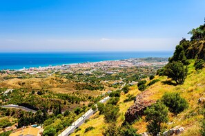 A coastal cityscape with a prominent road winding through hilly terrain. - Rancho Miraflores Seaview Townhouse (Mijas)