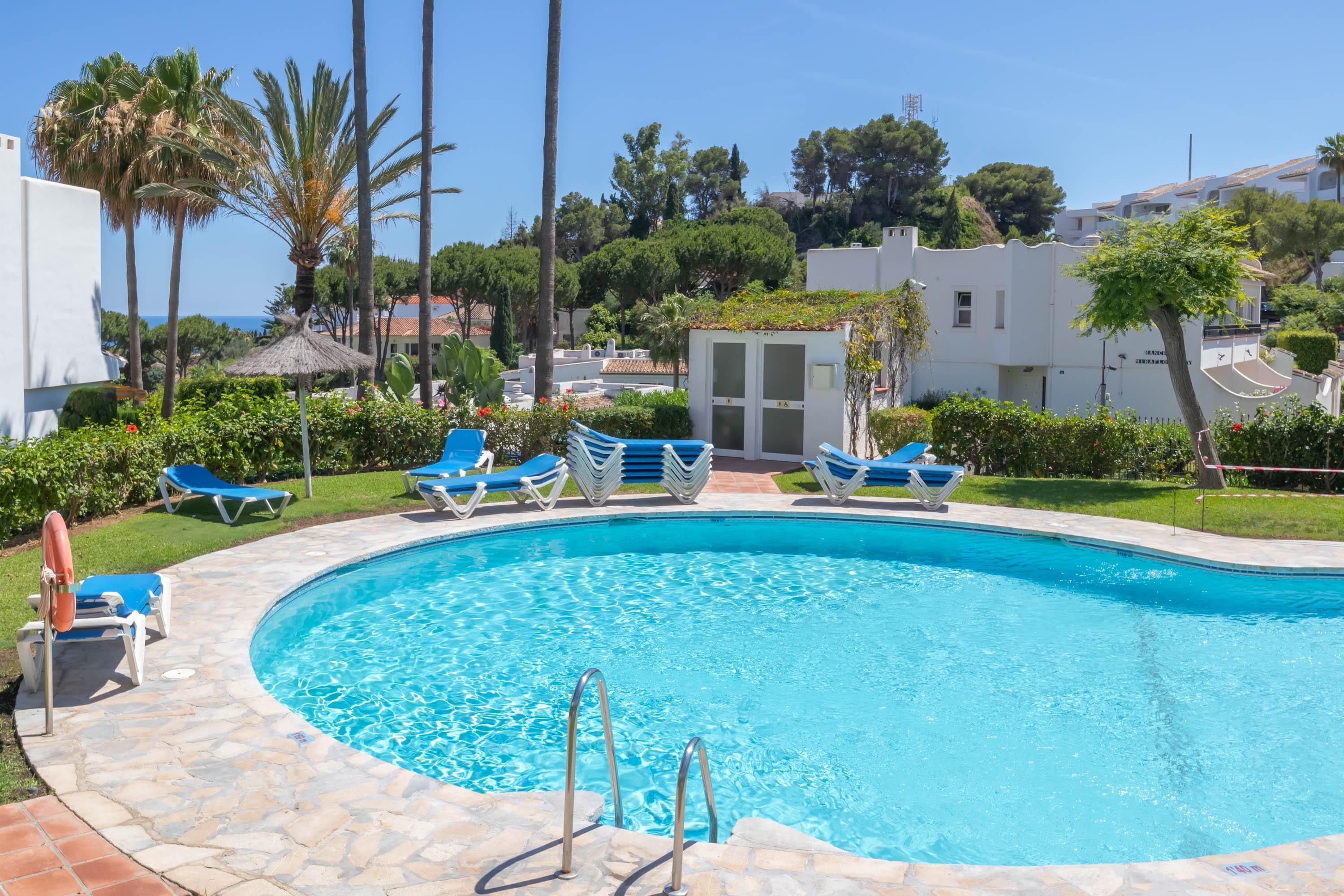 A swimming pool with blue lounge chairs and a lifeguard stand.