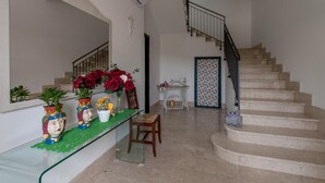 A staircase with a handrail, a small table with a vase of flowers, and a chair.