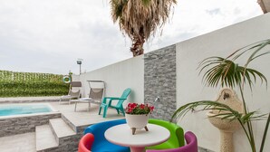 A poolside area with a stone wall, a small pool, and colorful chairs.