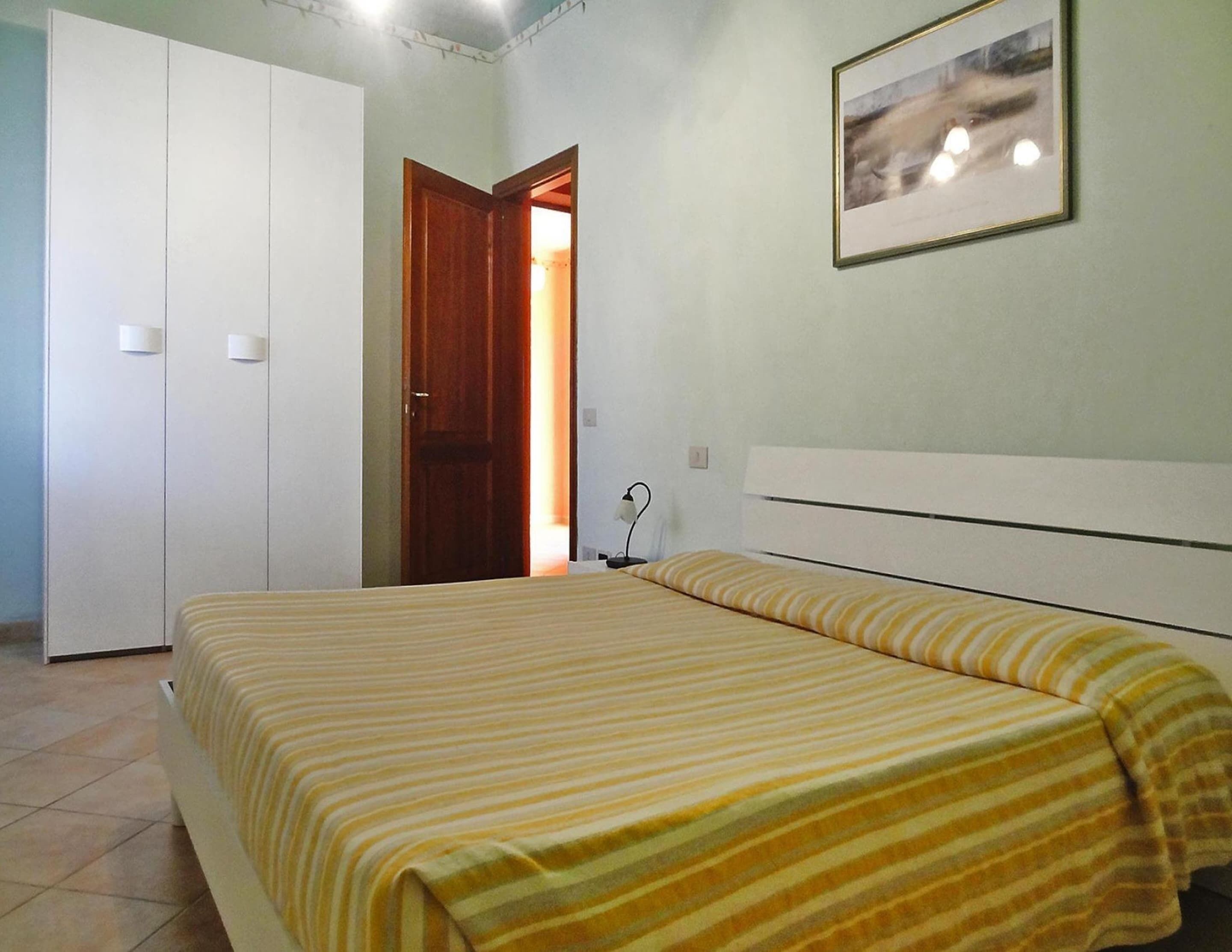 A bedroom with a bed, a wardrobe, and a door leading to another room.