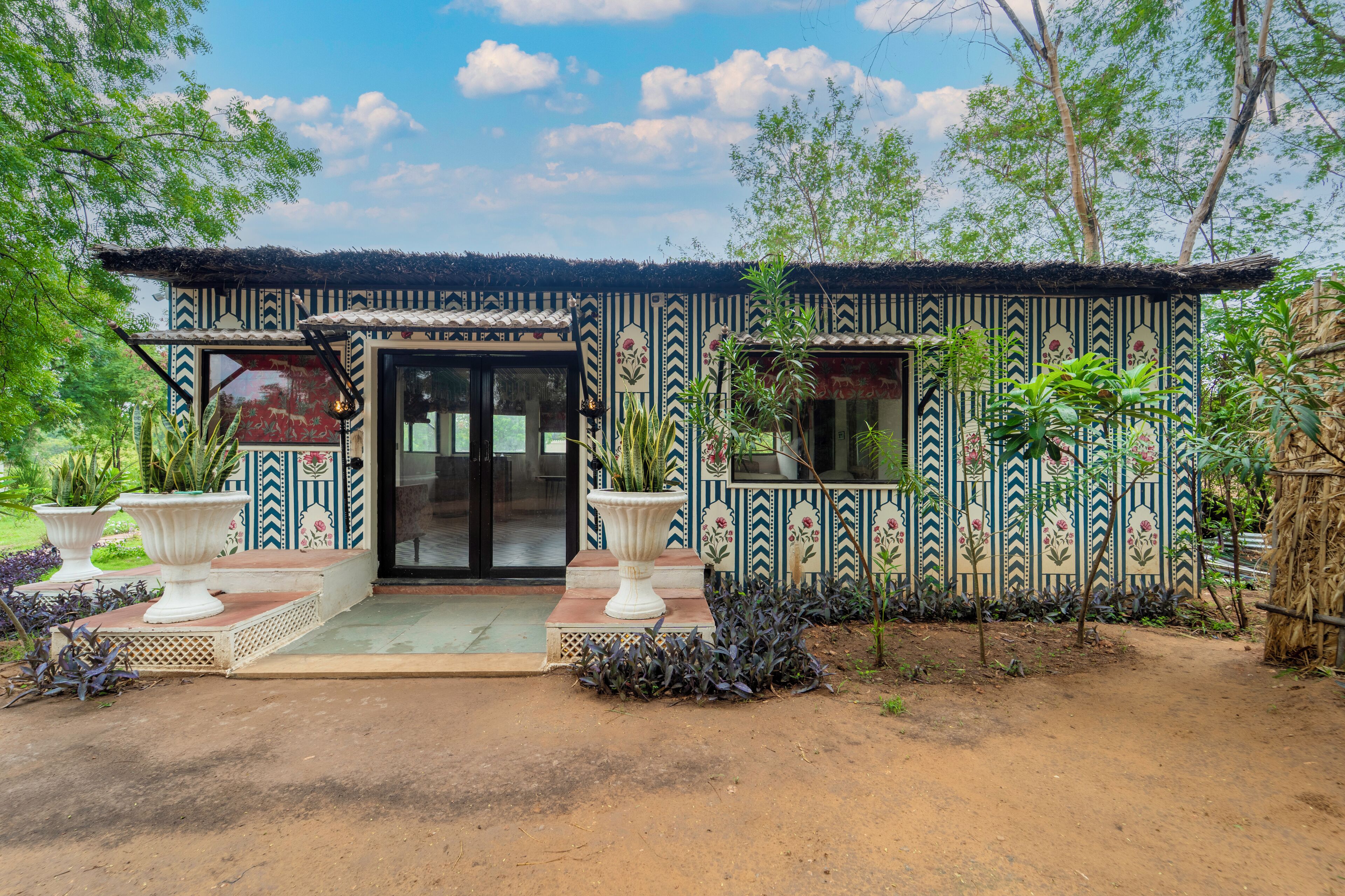 A traditional house with a patterned exterior, a front door, and potted plants.