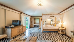 Un dormitorio con una cama, televisión, un aparador de madera y suelo estampado.