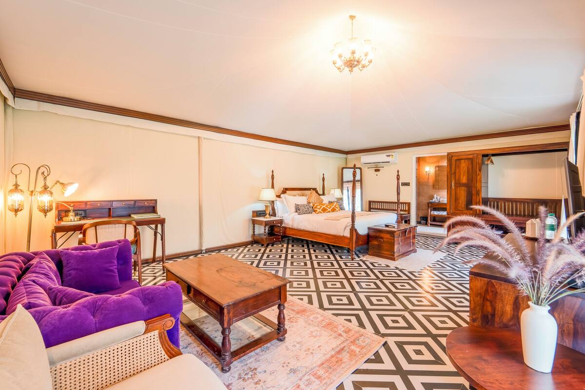 A room with a bed, a purple sofa, a wooden coffee table, and a patterned floor.