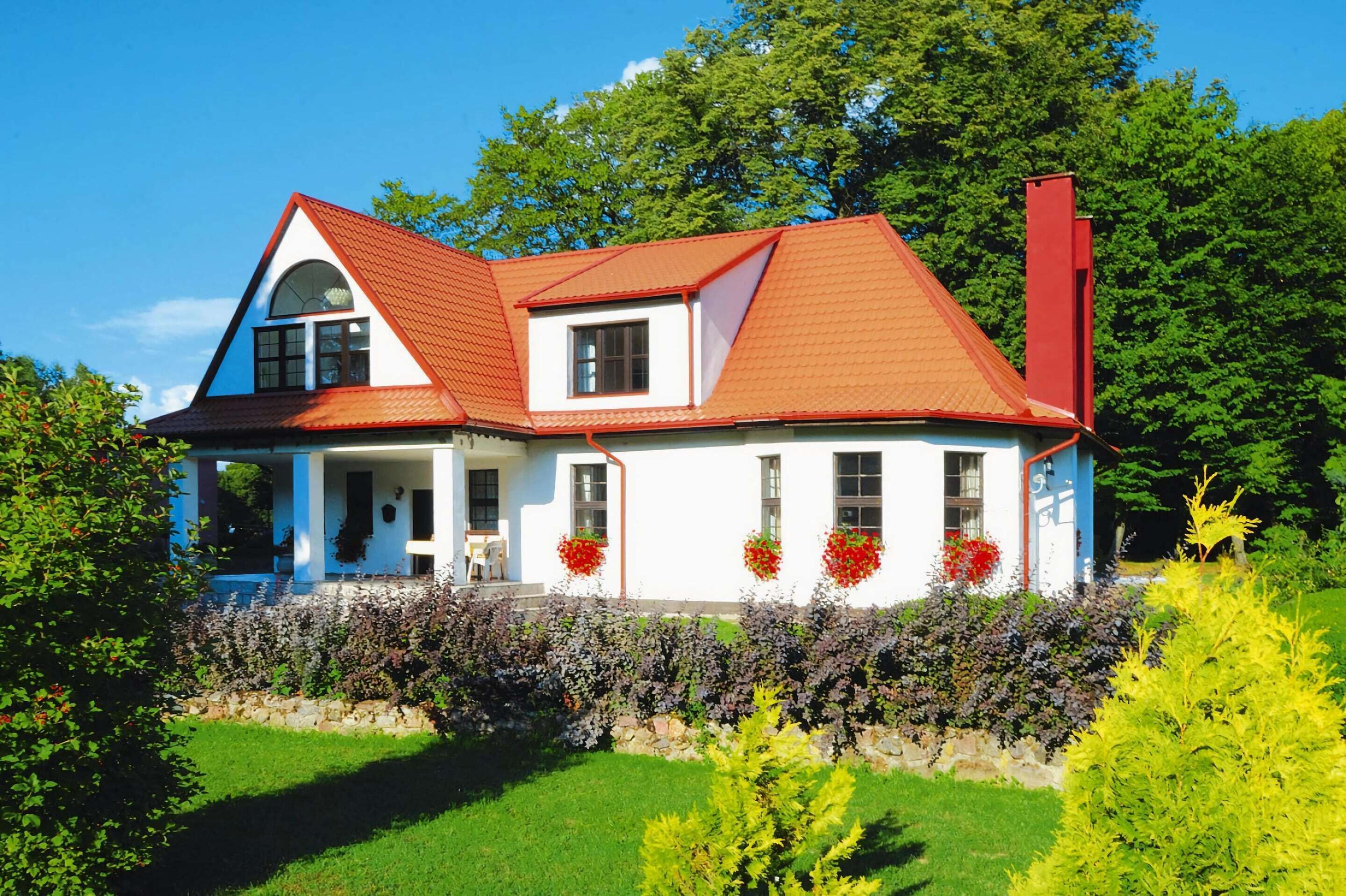 Ein zweigeschossiges Haus mit rotem Dach, weißen Wänden und einem Steinmauerwerk.