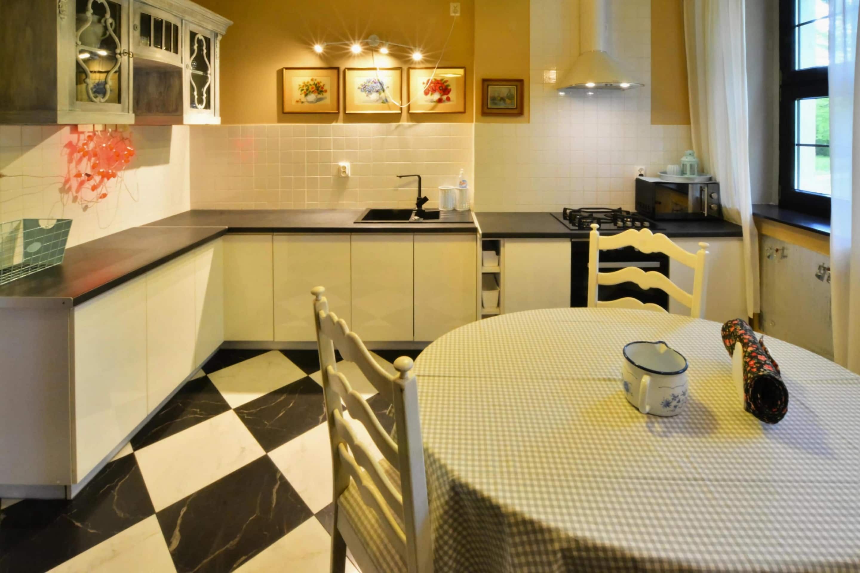 Una cocina con piso a cuadros, una mesa de comedor con mantel a cuadros y una estufa.