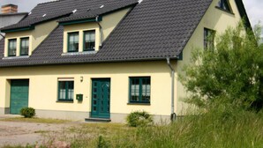 Ein zweistöckiges Haus mit einem geneigten Dach, grünen Fensterläden und einer grünen Tür.