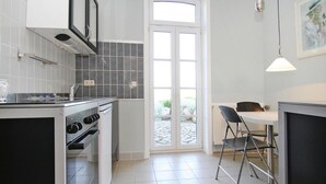 Ett kompakt kök med en spis, en ugn och en matplats med ett bord och stolar.