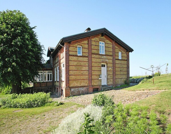 A two-story brick building with a gabled roof, a front door, and a small porch area.