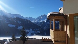 Un balcon en bois offrant une vue sur des montagnes enneigées et un ciel dégagé.