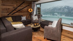 Un salon moderne doté d’une grande fenêtre donnant sur un paysage montagneux enneigé.