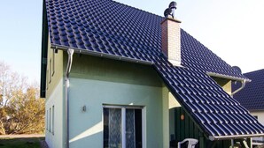 A house with a sloped roof, a chimney, and a sliding glass door. - Doppelhaushalfte, Zingst (Zingst)