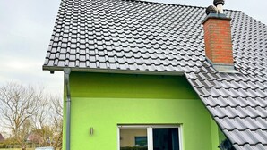 A house with a green exterior, a tiled roof, and a sliding glass door. - Doppelhaushalfte, Zingst (Zingst)
