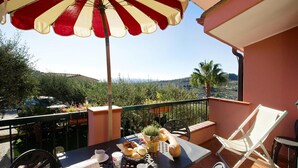 Ein Balkon mit einem Tisch, gedeckt für ein Frühstück, inklusive Brot, Gebäck und einer Kaffeetasse.
