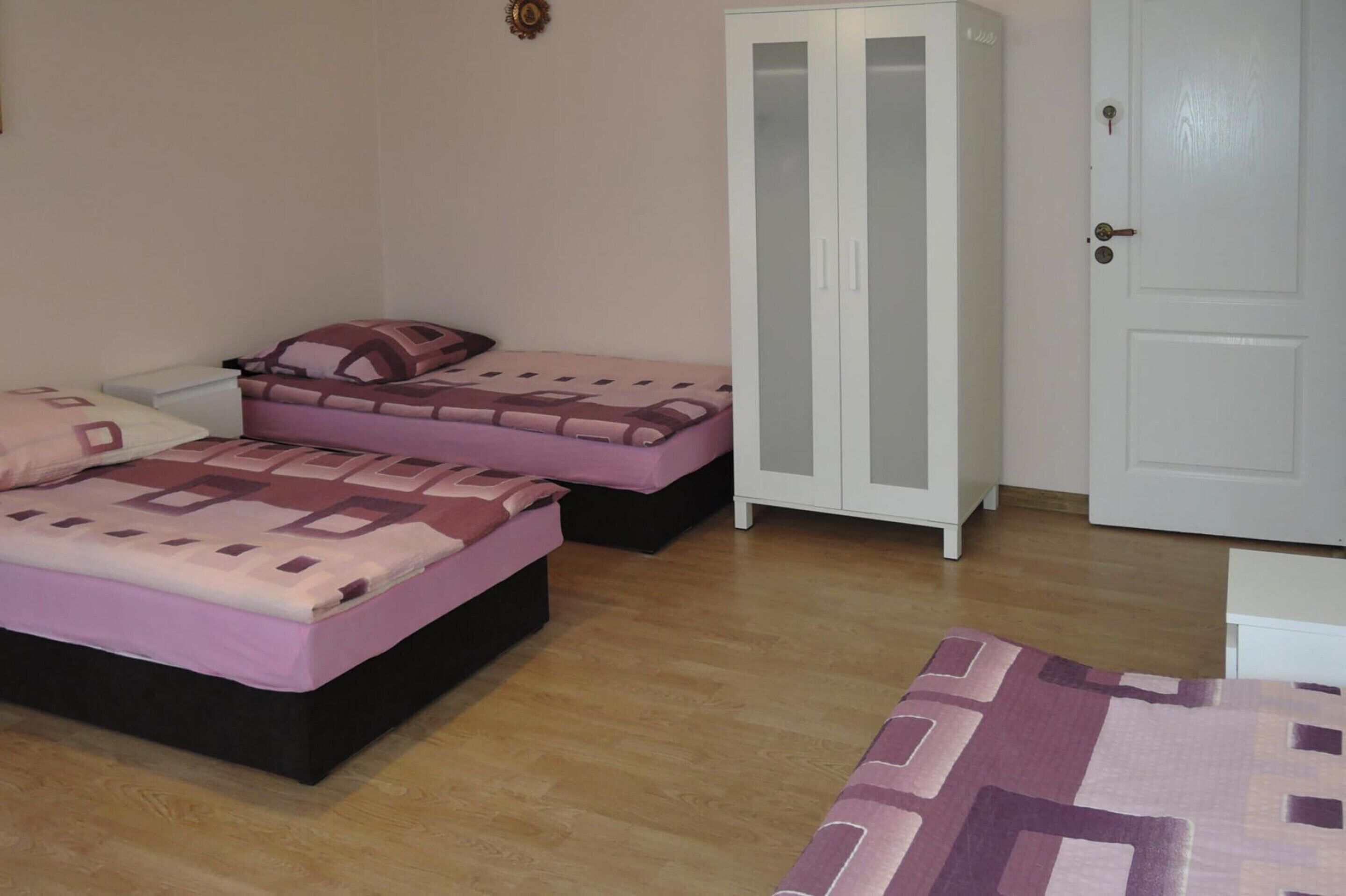 Una camera da letto con due letti, un armadio e una porta.