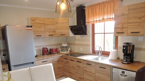 A modern kitchen with wooden cabinets, a refrigerator, a coffee maker, and a dishwasher. - House in Stepnica With Sauna and Jacuzzi (Stepnica)
