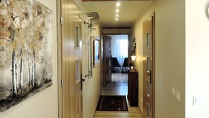 A hallway with wooden doors, a painting, and a rug leading to a room with two chairs and a lamp. - House in Stepnica With Sauna and Jacuzzi (Stepnica)