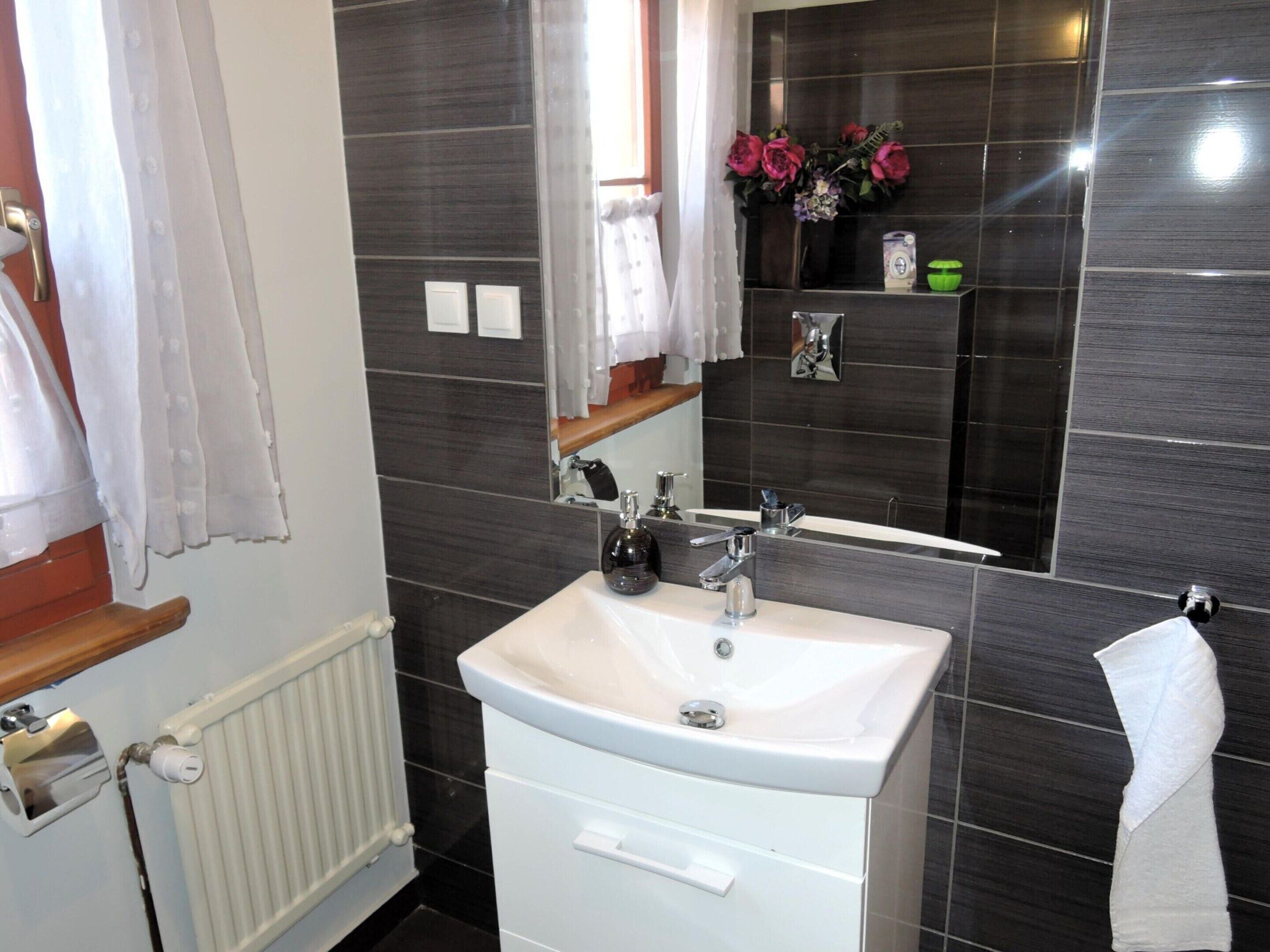 A bathroom with a white sink, a mirror, a towel rack, and a radiator.