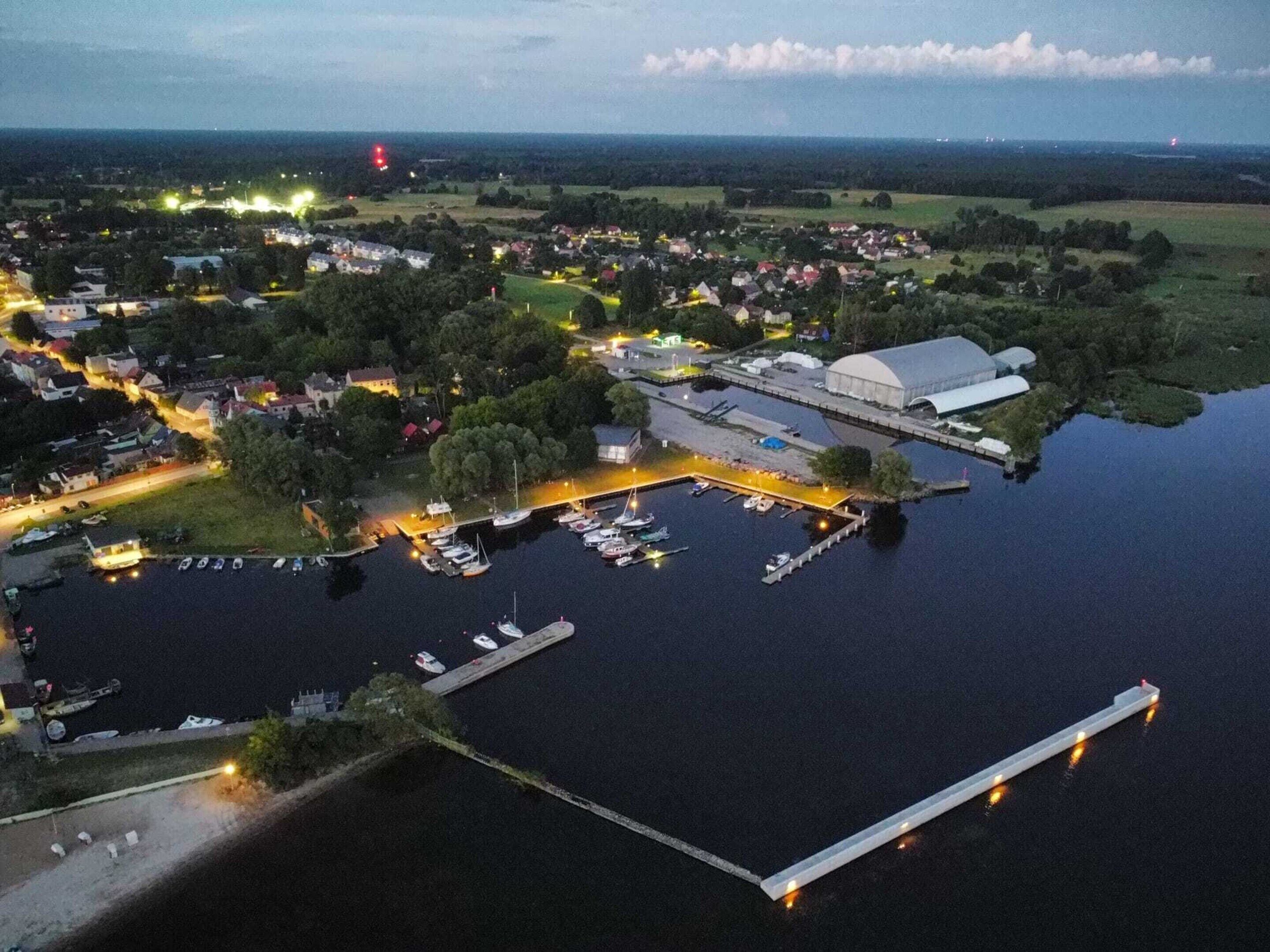 An aerial view of a marina with boats docked, a large covered structure, and surrounding residential areas.