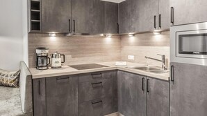 Uma cozinha moderna com armários escuros, micro-ondas embutido e cafeteira.
