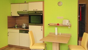 A compact kitchen with a dishwasher, oven, and a small dining table with two chairs. - Apartments Spreeidyll, Schlepzig (Schlepzig)