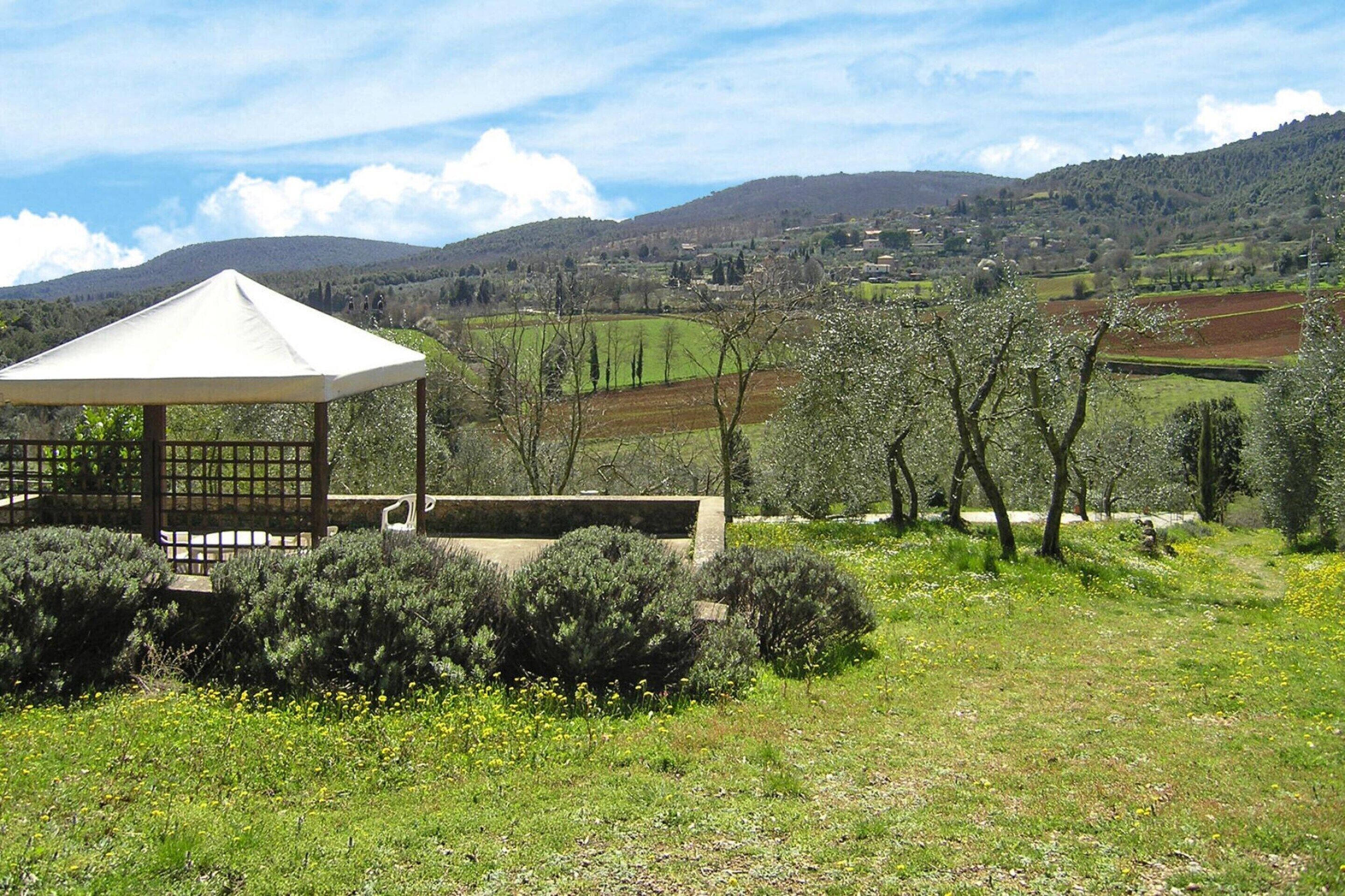 A gazebo in a rural landscape with fields and hills in the background.