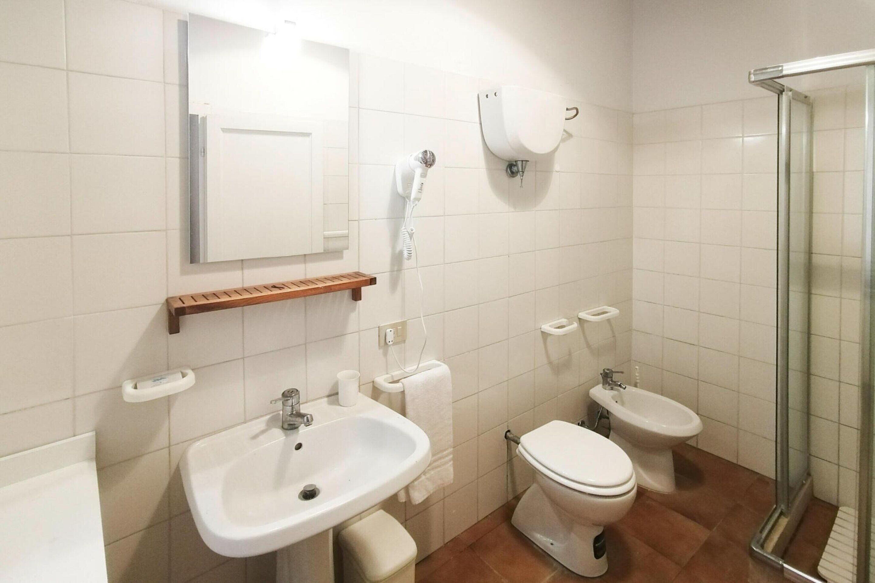 A bathroom with a sink, toilet, bidet, and a glass shower enclosure.