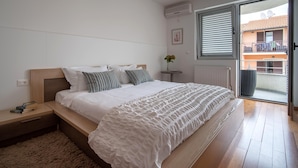 A bedroom with a bed, bedside table, and a view of the outside balcony. - Villa in Rovinj Near Beach & Old Town (Rovinj)