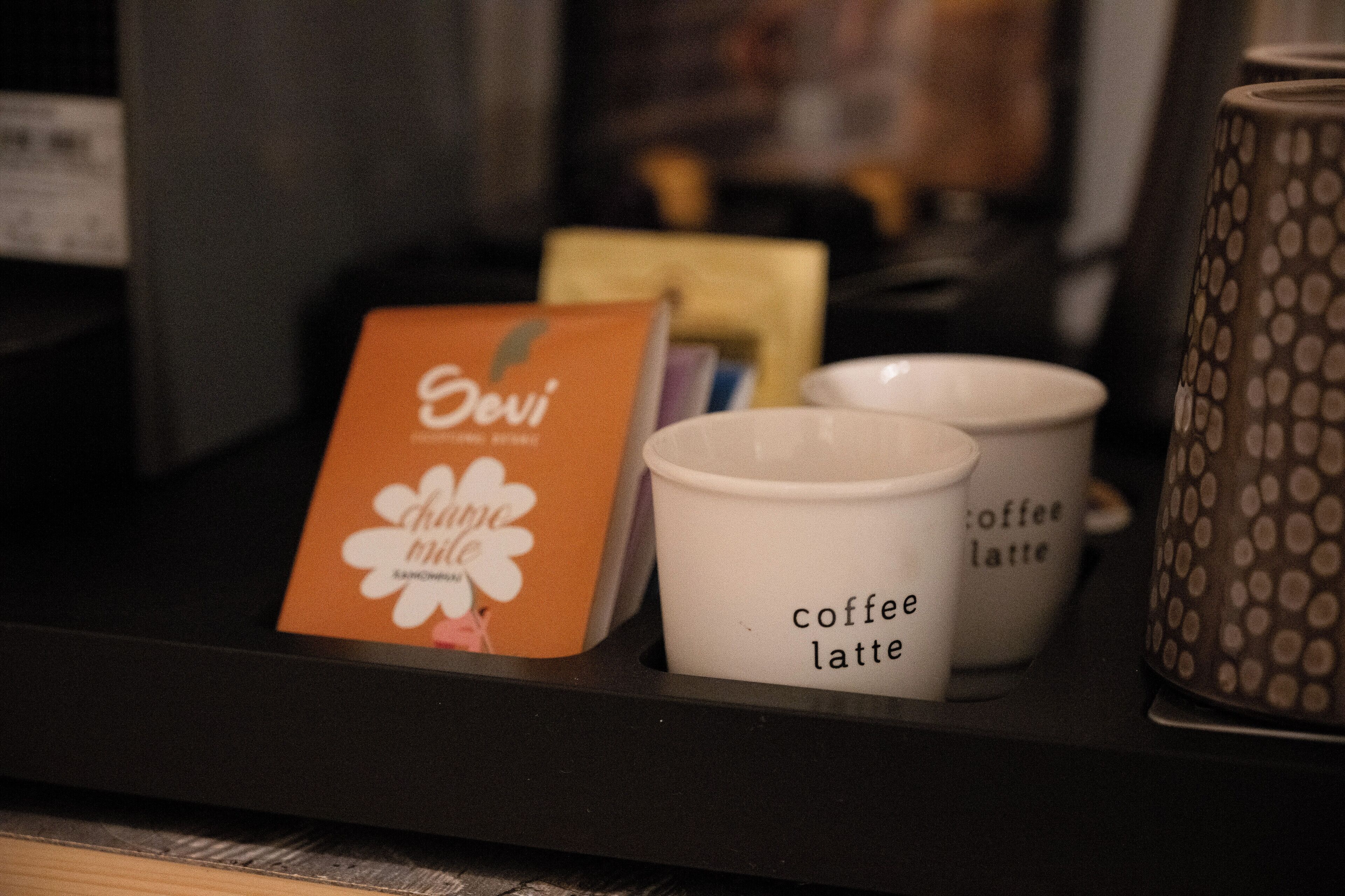 A coffee machine with a card and two coffee cups labeled "coffee latte" on a counter.