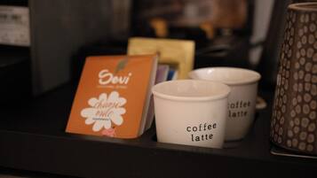 A coffee machine with a card and two coffee cups labeled "coffee latte" on a counter.