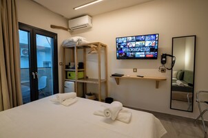 Habitación de hotel con cama, televisor montado en la pared, estante de madera y espejo.