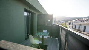 Ein Balkon mit Tisch und Stühlen, Blick auf die Stadt und ein Gebäude mit grüner Fassade.