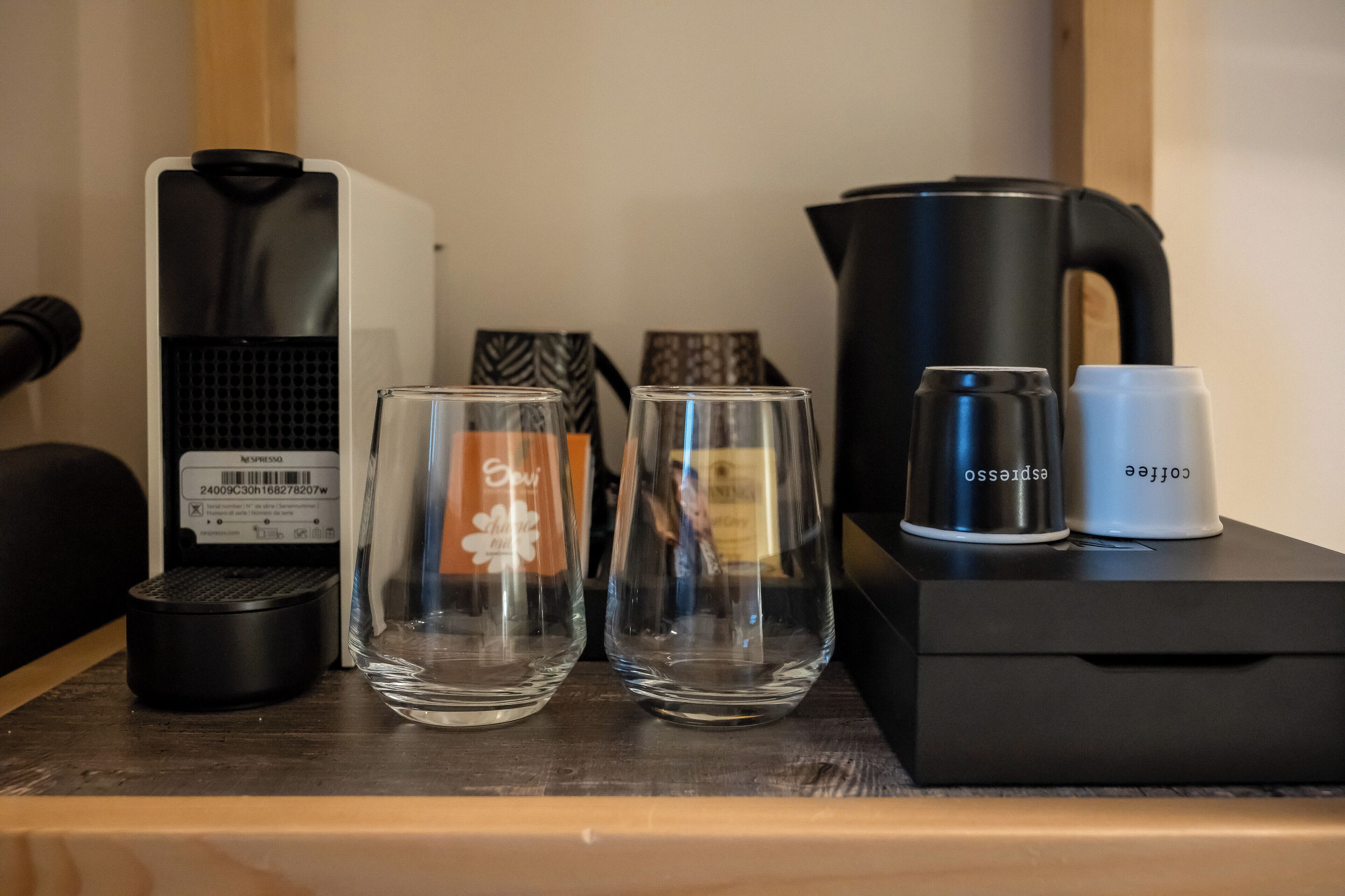 Una cafetera, dos vasos y un hervidor sobre una mesa de madera.