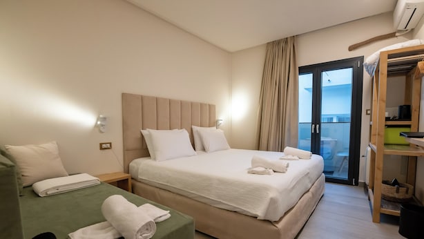 Ein Hotelzimmer mit zwei Betten, einem Balkon und einem Kleiderschrank.