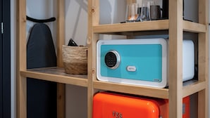Eine kleine Küche mit einem türkisfarbenen und weißen Kühlschrank, einem orangefarbenen TZS-Gerät und einer Holzablage mit Korb und Gläsern.