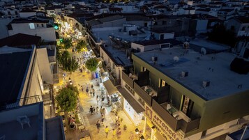 Escena de una calle concurrida con tiendas, cafés, una farmacia y una panadería.