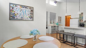 A dining area with a wooden table, white placemats, and a vase of flowers. A bulletin board with various papers and a map is on the wall. - Spacious 4 bdrm home, Close to Lake, Wine, Downtown, Kid Friendly, Self Checkin (Geneva)