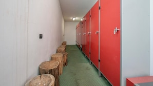Un couloir avec des casiers et des tabourets en bois.