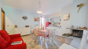 En hyggelig stue med en rød sofa, et spisebord med stole, og et køkkenområde med skabe og en pejs.