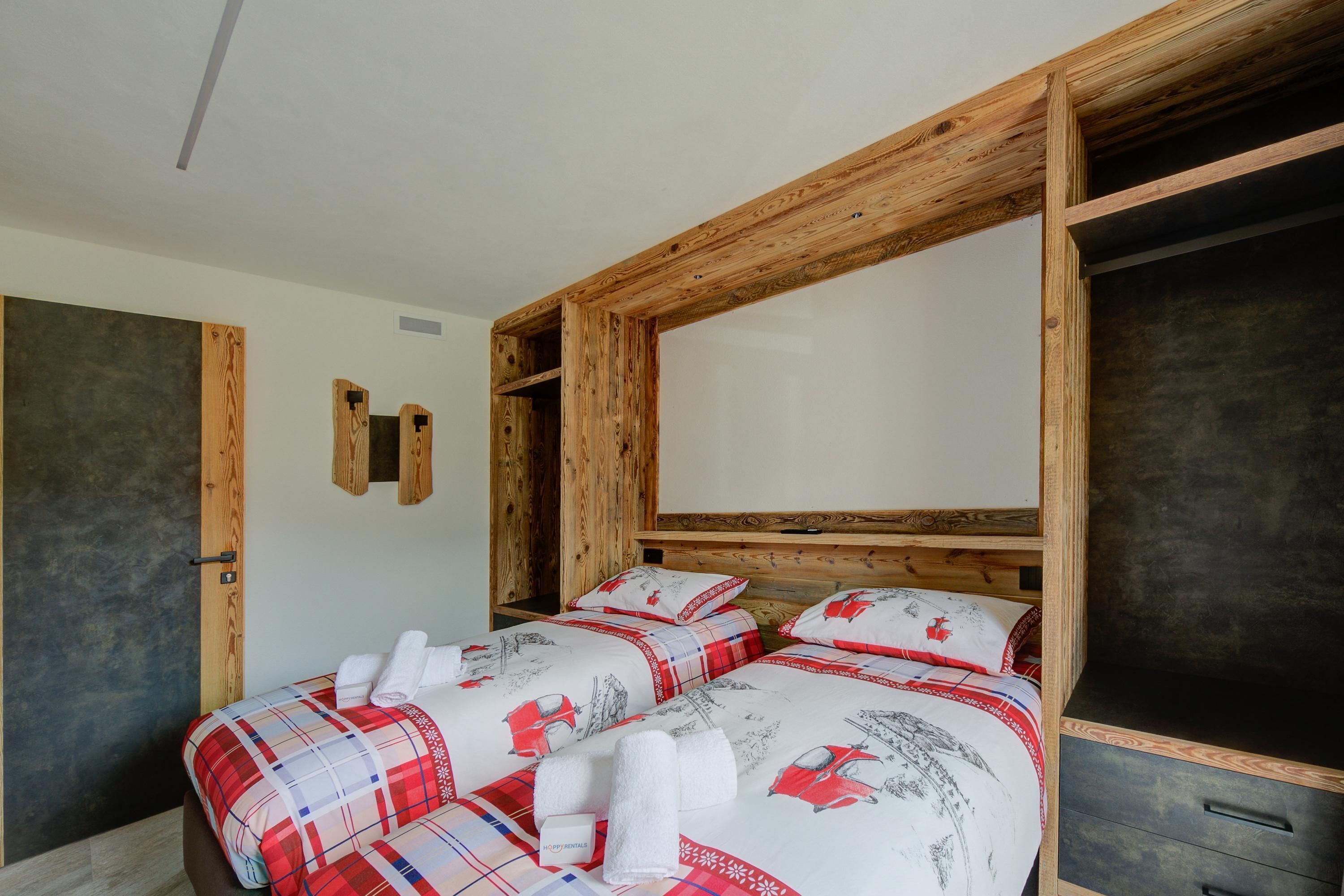 Habitación con dos camas, cabecero de madera y pared oscura.