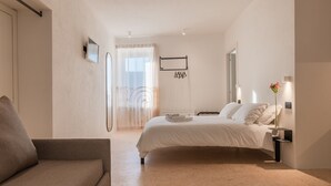 A modern bedroom with a bed, a sofa, and a nightstand with a lamp.