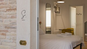 Et soveværelse med en seng, et natbord, et spejl og en hængende lampe.