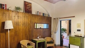 A cozy room with wooden paneling, two wicker chairs, a small table with a lamp, and a green cabinet. - Deliziosa Camera in Agriturismo a 7 km da Firenze (Toscana)