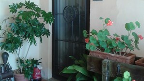 A door with a metal gate, potted plants, and a fire extinguisher on the ground. - Deliziosa Camera in Agriturismo a 7 km da Firenze (Toscana)