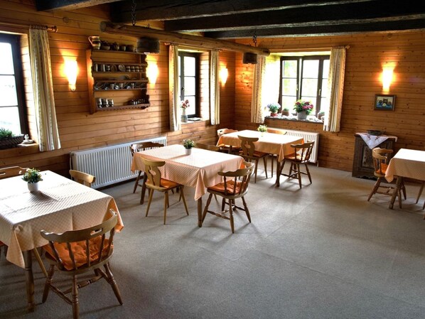 A cozy dining area with wooden walls, multiple tables, and chairs. - Farmhouse in Nockberge Near Ski Slopes (Treffen)