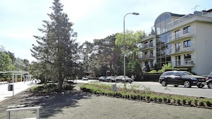 A street with parked cars, a large tree, and a building with balconies. - Holiday Appartment at the Promenade, Swinoujscie (Swinoujscie)