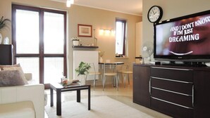 A living room with a sofa, coffee table, TV, and a dining area with chairs and a table. - Holiday Appartment at the Promenade, Swinoujscie (Swinoujscie)