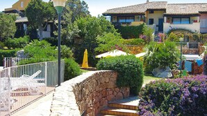 A courtyard with stone steps, a lamp post, and a pool area with lounge chairs. - Apartment in Porto Rotondo Near the Beach (Olbia)